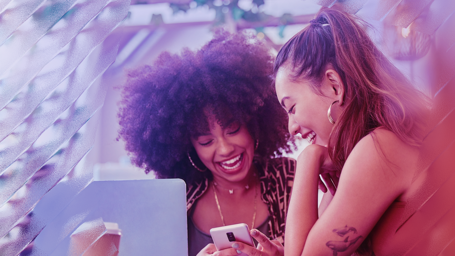 Image of two happy friends looking at a phone together.