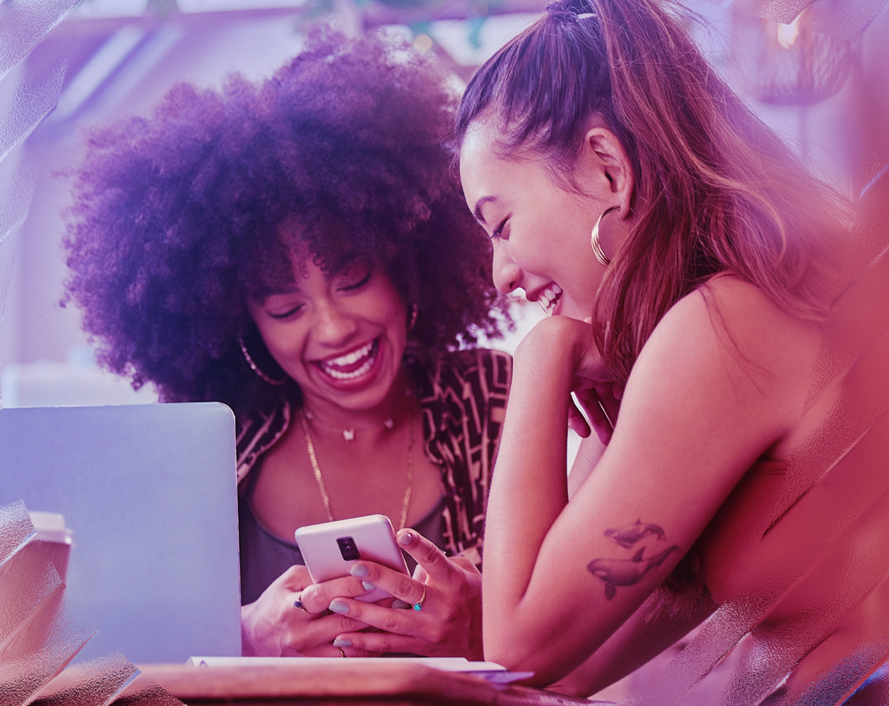 Image of two happy friends looking at a phone together.
