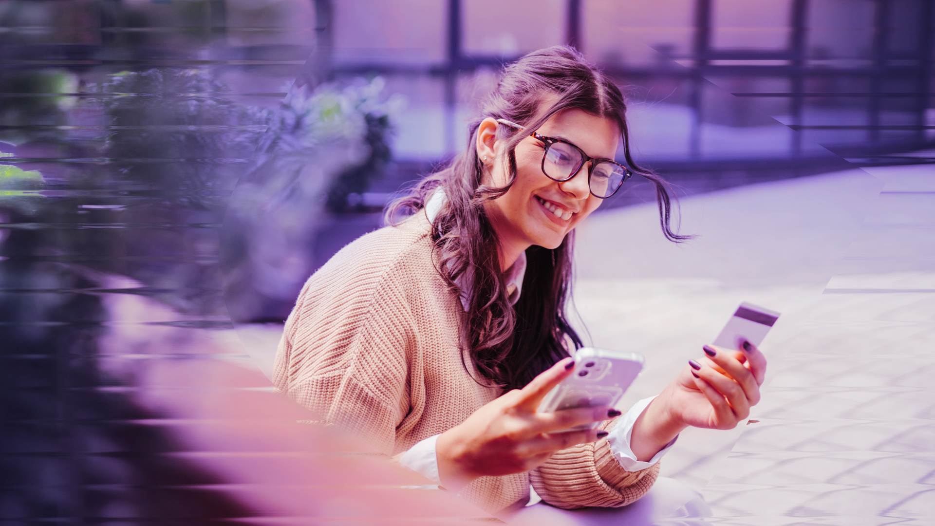 Image of a happy woman using her credit card and her phone.