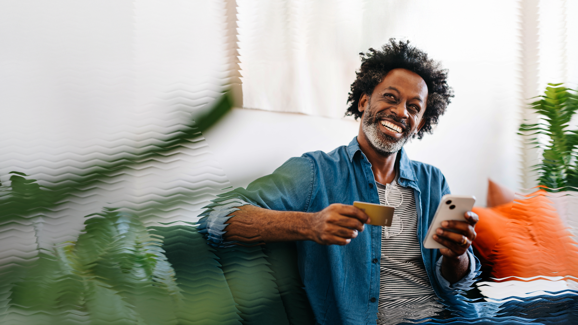 Image of a happy man holding a phone and a credit card.