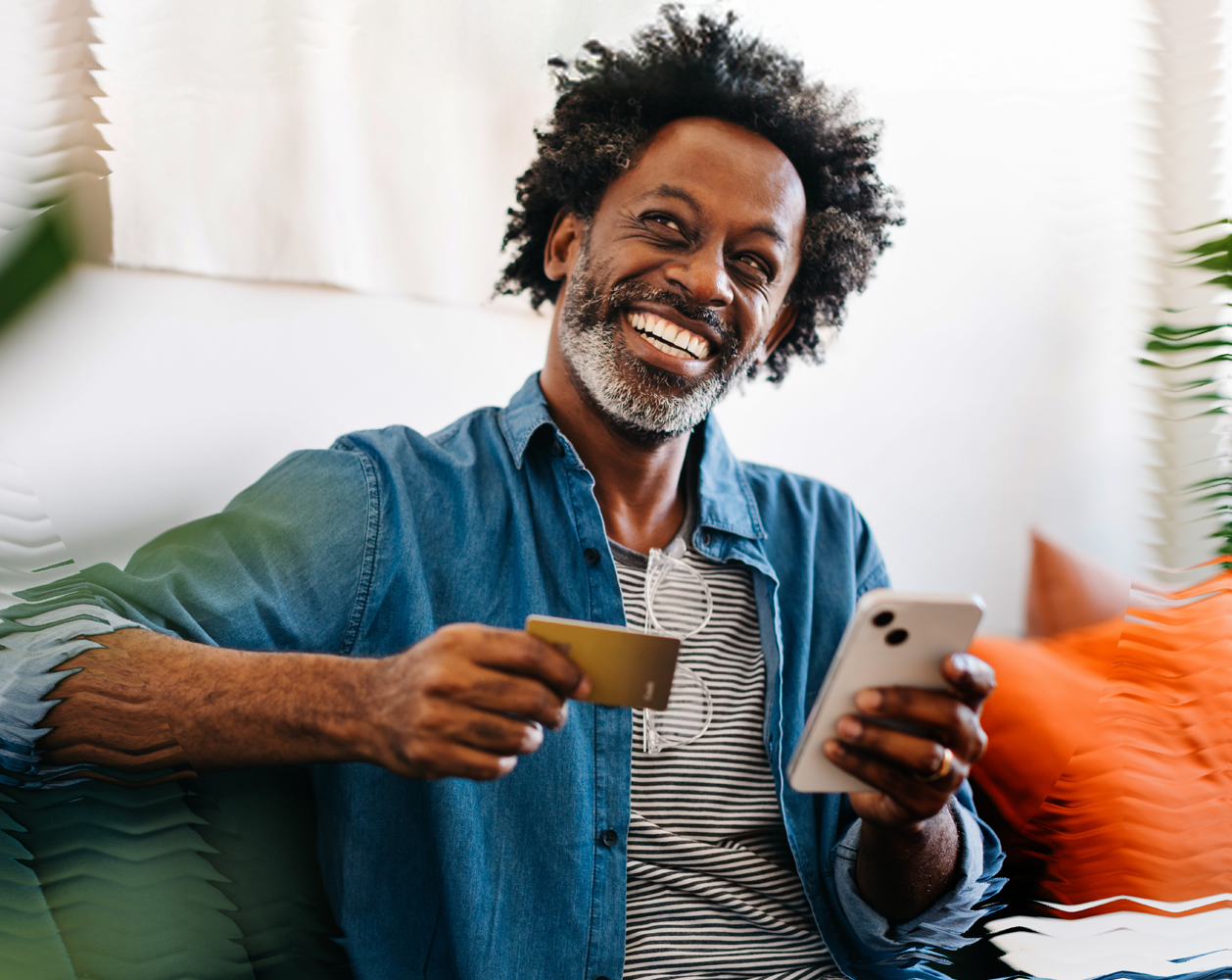 Image of a happy man holding a phone and a credit card.