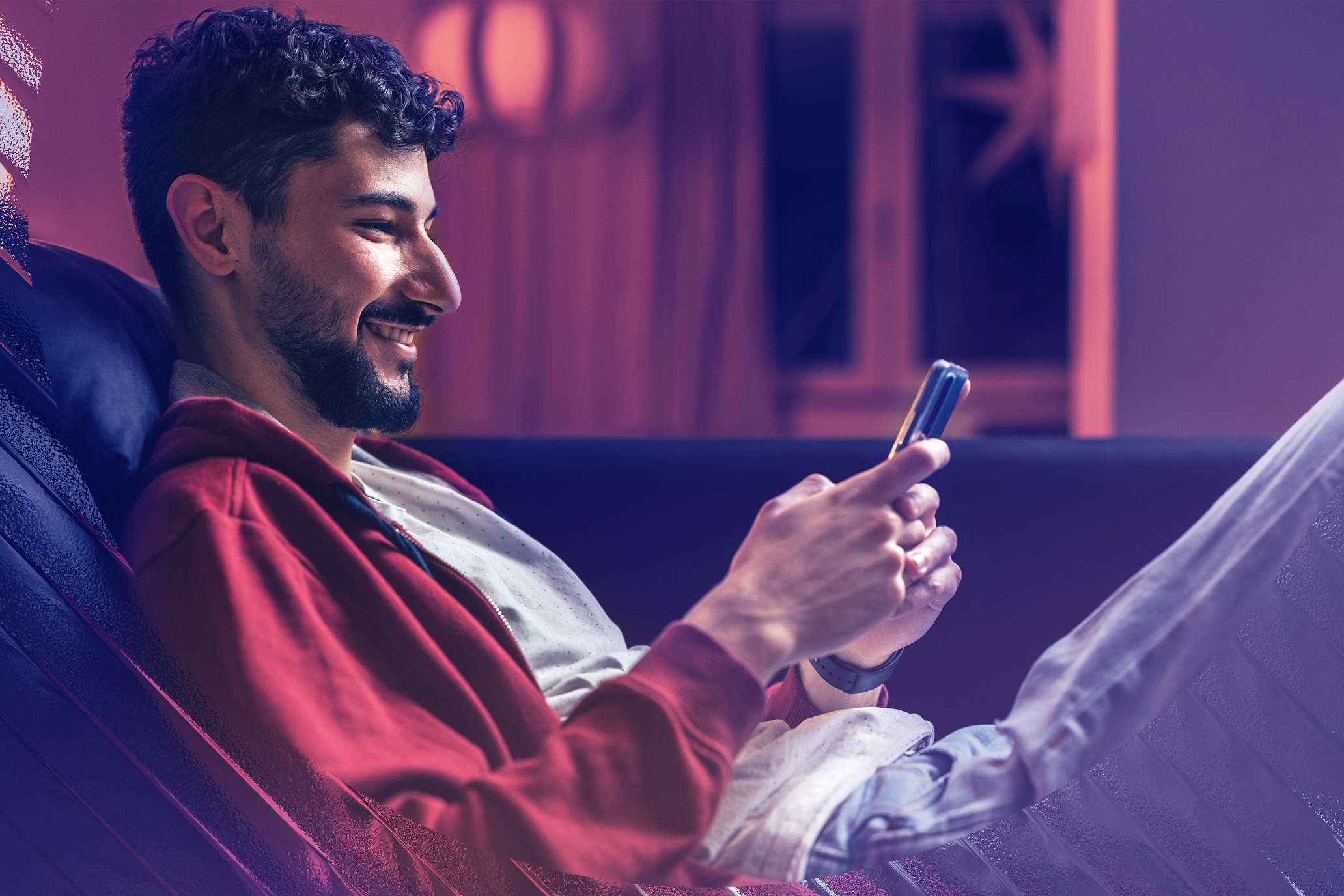 Image of a happy man on his phone while sitting on the couch.